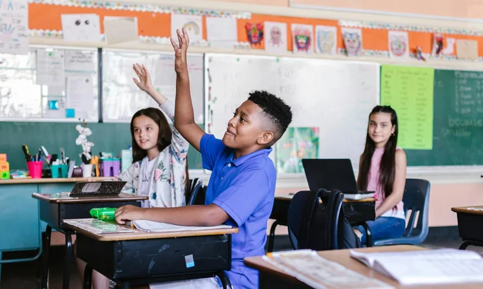 Confident child raising hand in classroom