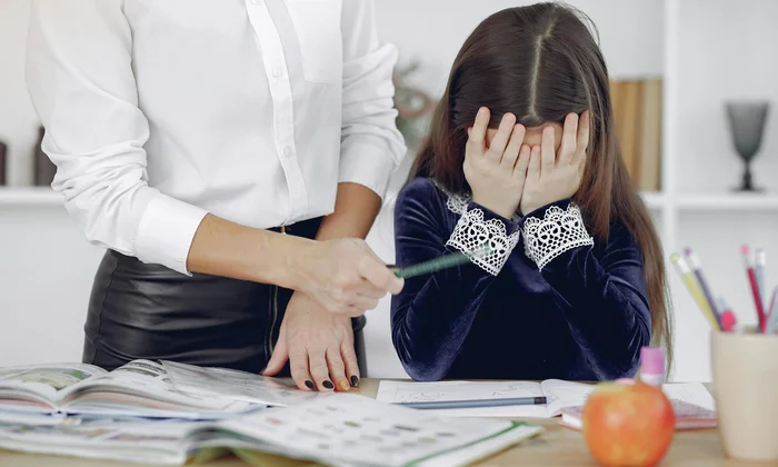 Child frustrated over schoolwork with adult nearby