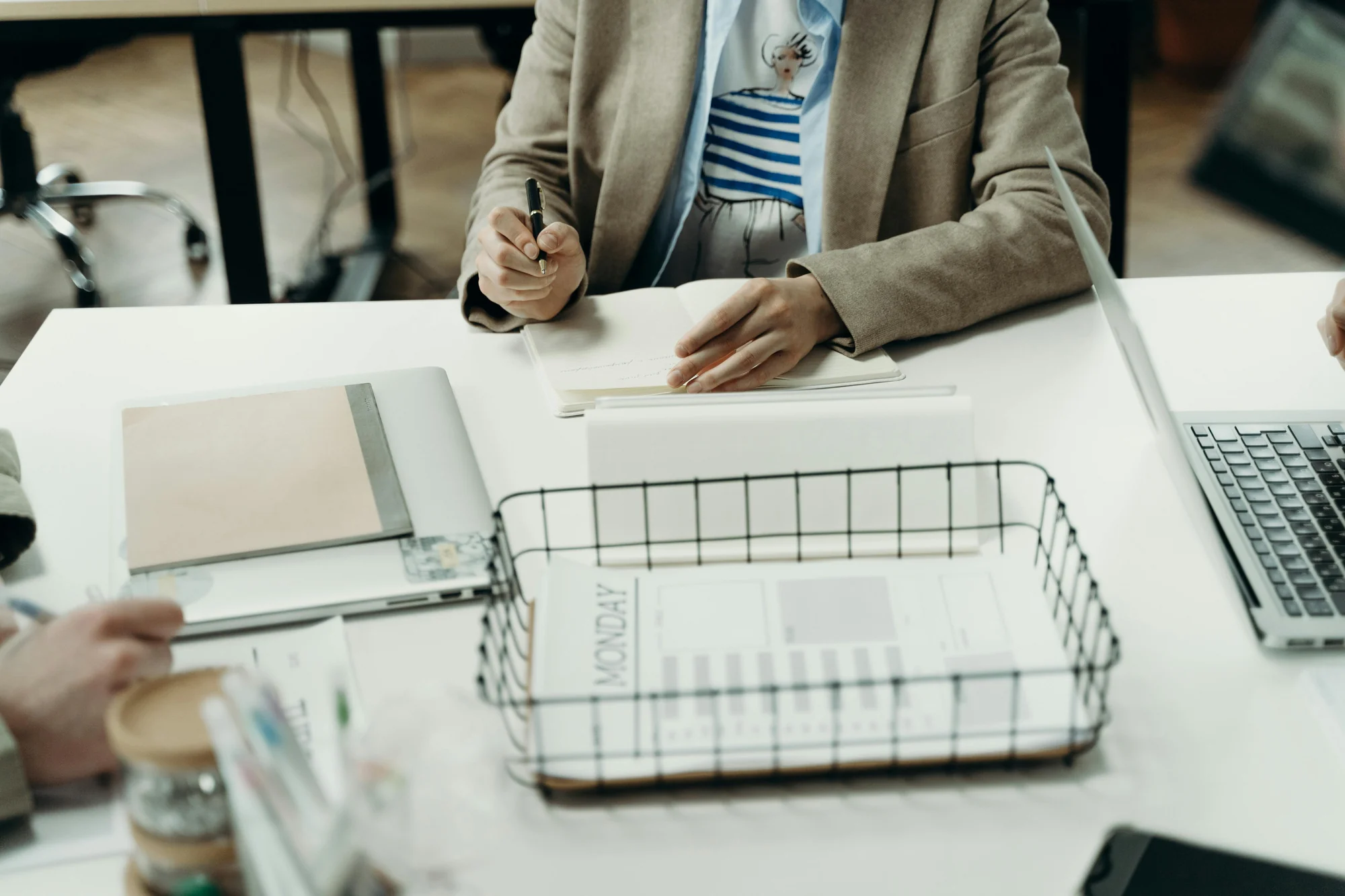Parent writing notes on a notepad with a pen, preparing an agenda for an IEP meeting