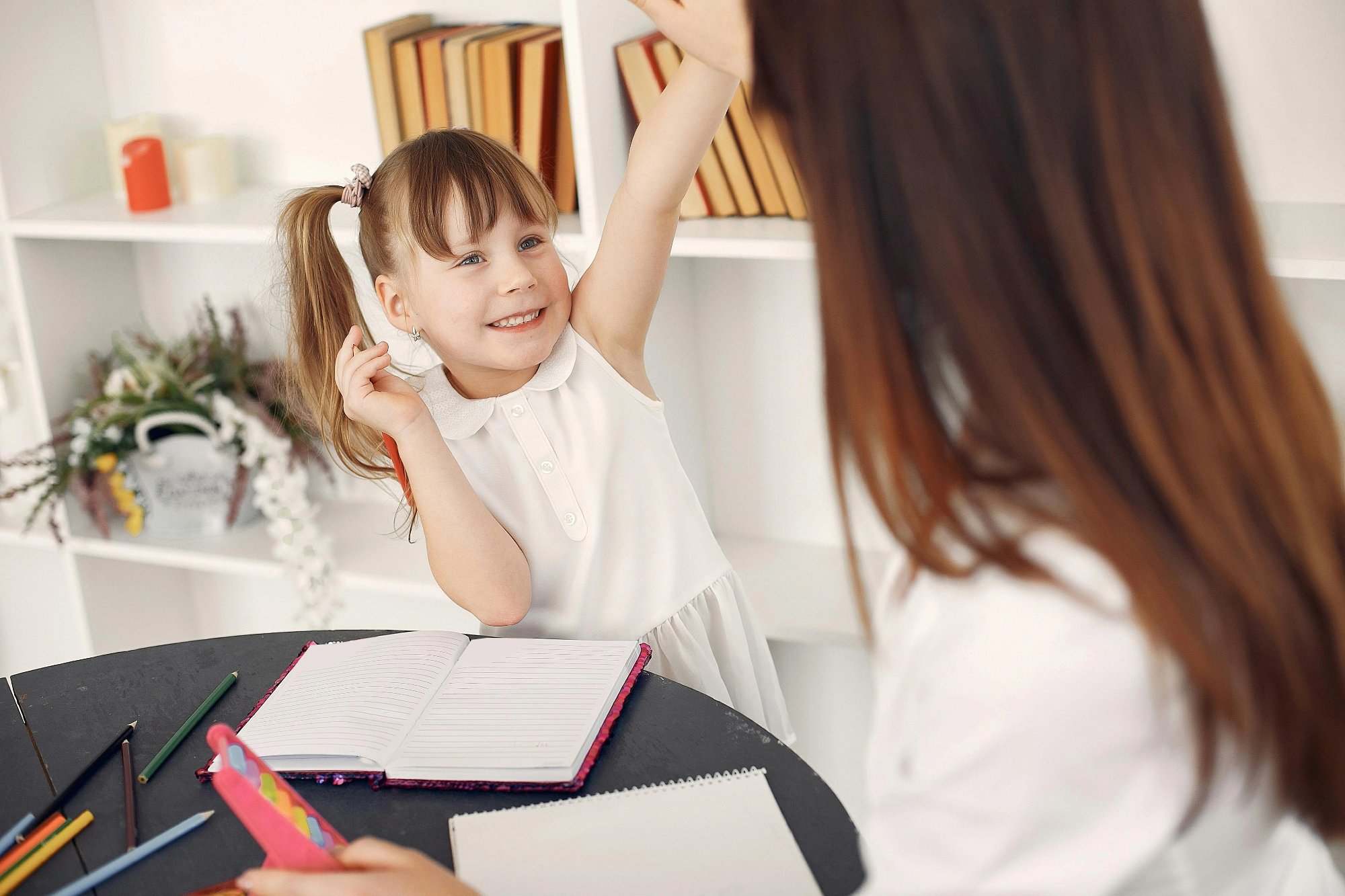 Young girl enthusiastically participating in a one-on-one speech therapy session with an adult
