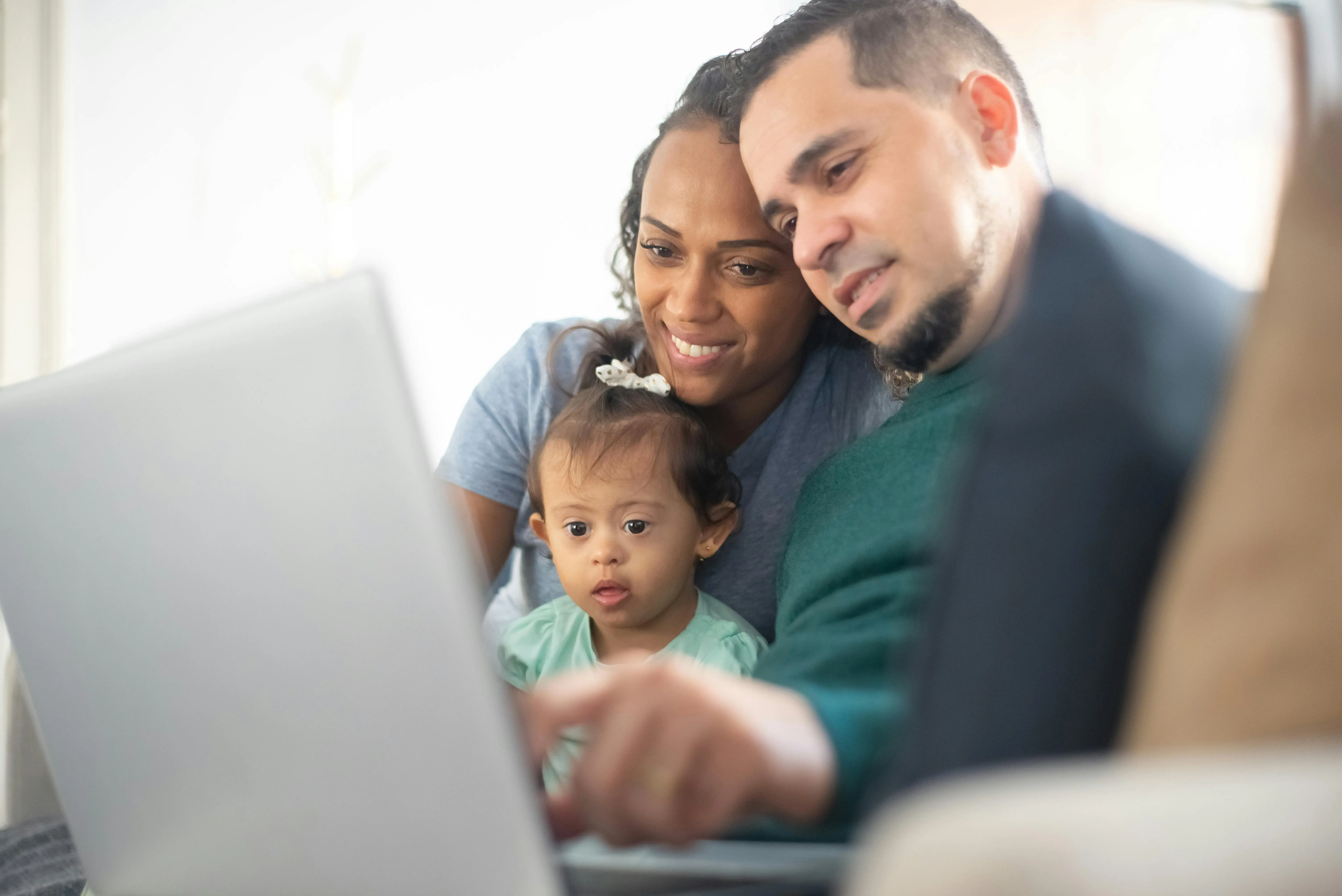 Familia latina con niña con síndrome de Down mirando IEP Desk en el ordenador